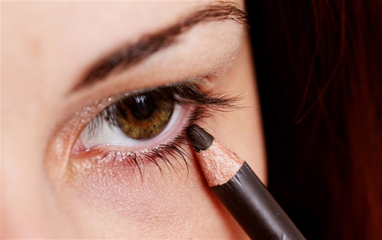 महिला applying eyeliner