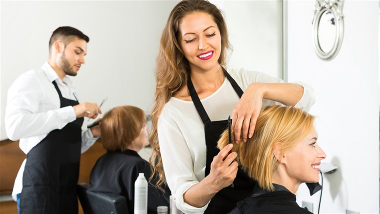 מחייך client sitting in a hair salon while hairdresser is combing her hair. Focus on client; Shutterstock ID 301639736; PO: TODAY.com