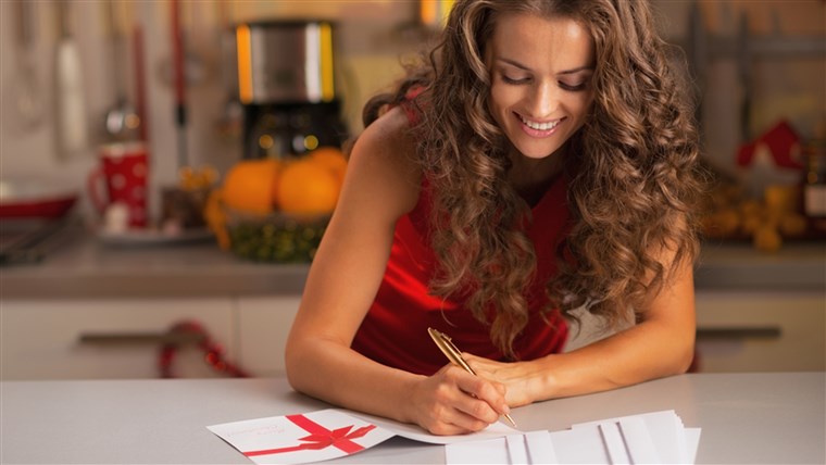 שמח young housewife signing christmas postcards in kitchen; Shutterstock ID 158618495; PO: TODAY.com