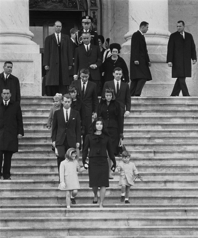 कैनेडी family members descend steps in Washington, Nov. 25, 1963, at the funeral for President John F. Kennedy. From front to back at left are: Caroline Kennedy, Jacqueline Kennedy and John Kennedy Jr.; behind them, Robert F. Kennedy, Patricia Kennedy Lawford and her husband, Peter Lawford; Little Sydney Lawford is at left of her mother. Behind Mrs. Kennedy are Jean Kennedy Smith and her husband Stephen E. Smith. Near top are President Lyndon B. Johnson and his wife Lady Bird Johnson. Behind the vice president is the chairman of the Joint Chiefs of Staff, Maxwell D. Taylor.