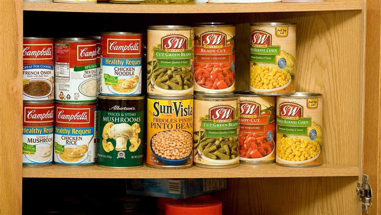 लकड़ी का kitchen cupboard with shelves full of canned soup and vegetables