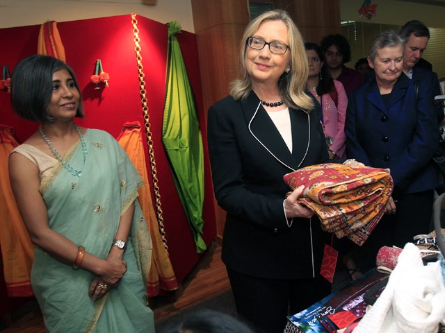 वह might be going easy on the makeup, but she still has an eye for colorful fashion: Clinton holds a sari in Kolkata, India, on May 6.