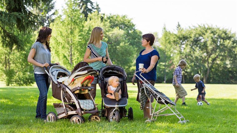 माताओं with baby strollers talking in park