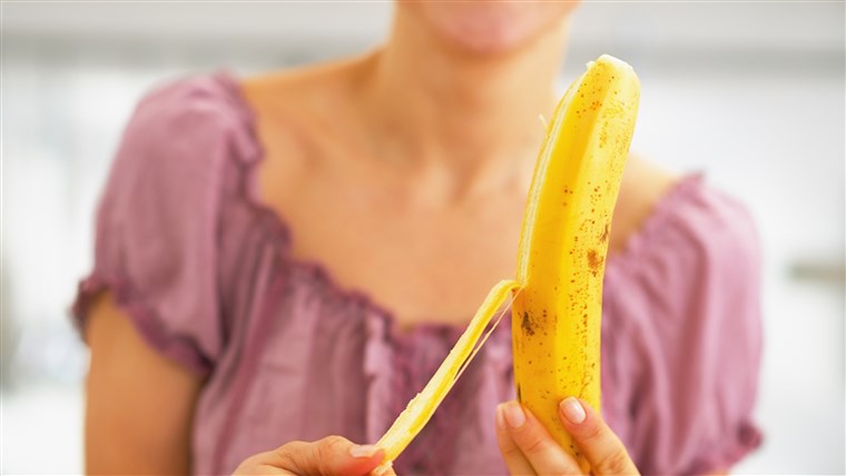 क्लोज़ अप on young woman peeling banana