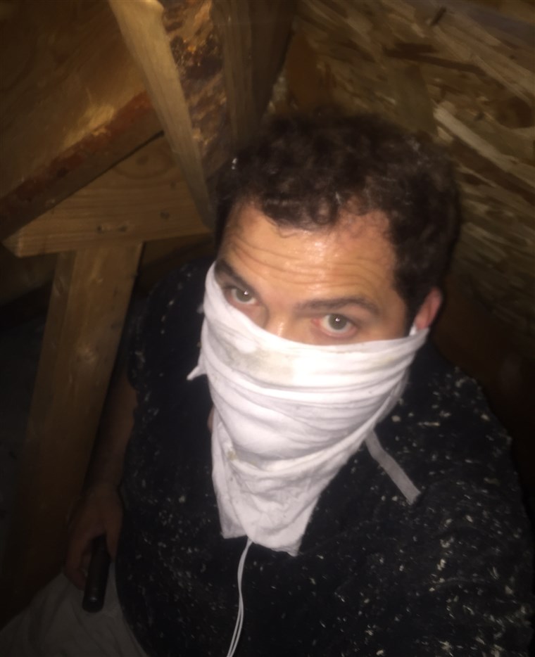 कौन is that masked man? It's the Singing Contractors' Josh Arnett, who protects himself while doing mold remediation treatment in an attic.