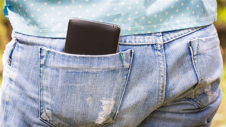 मोबाइल phone in the back pocket of blue jeans